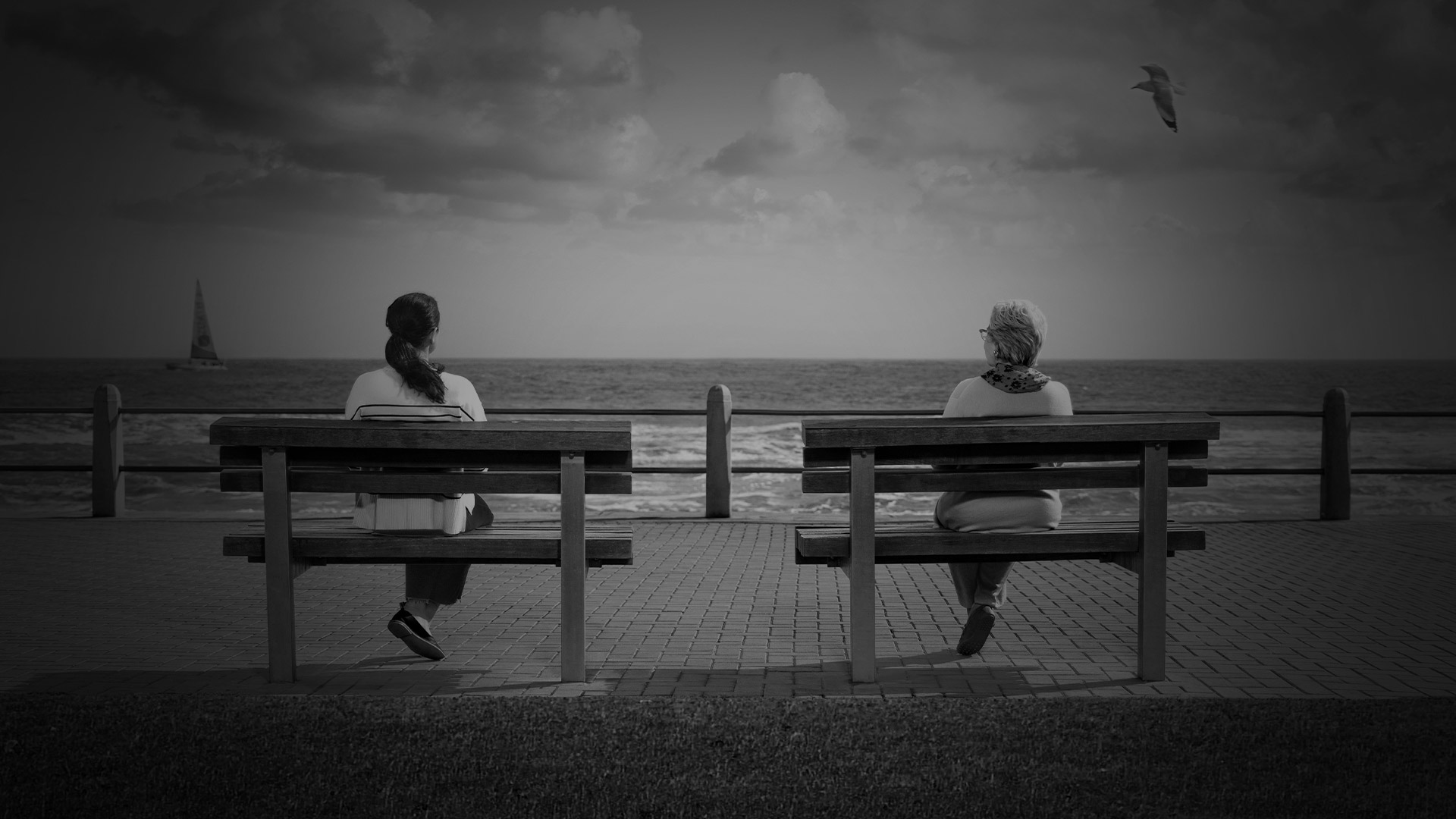Two people sitting alone on two different benches